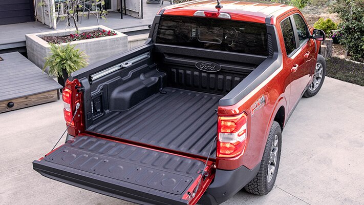 A red Ford Maverick is parked with its tailgate down.