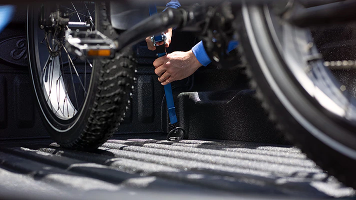 A bicycle is tied down and ratcheted securely inside the cargo bed.