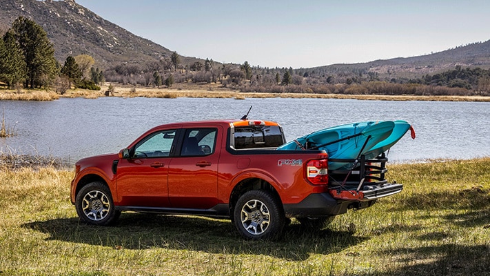 The Maverick® truck loaded up with a kayak sits parked besides a lake.