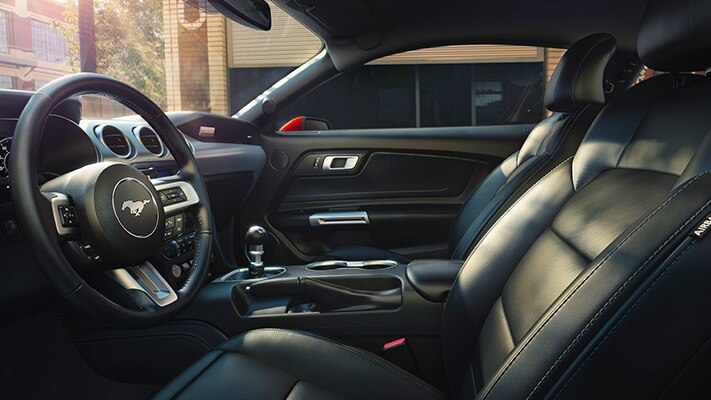 The interior of a 2023 Ford Mustang® coupe steering wheel, front seats, and center console with optional equipment shown.