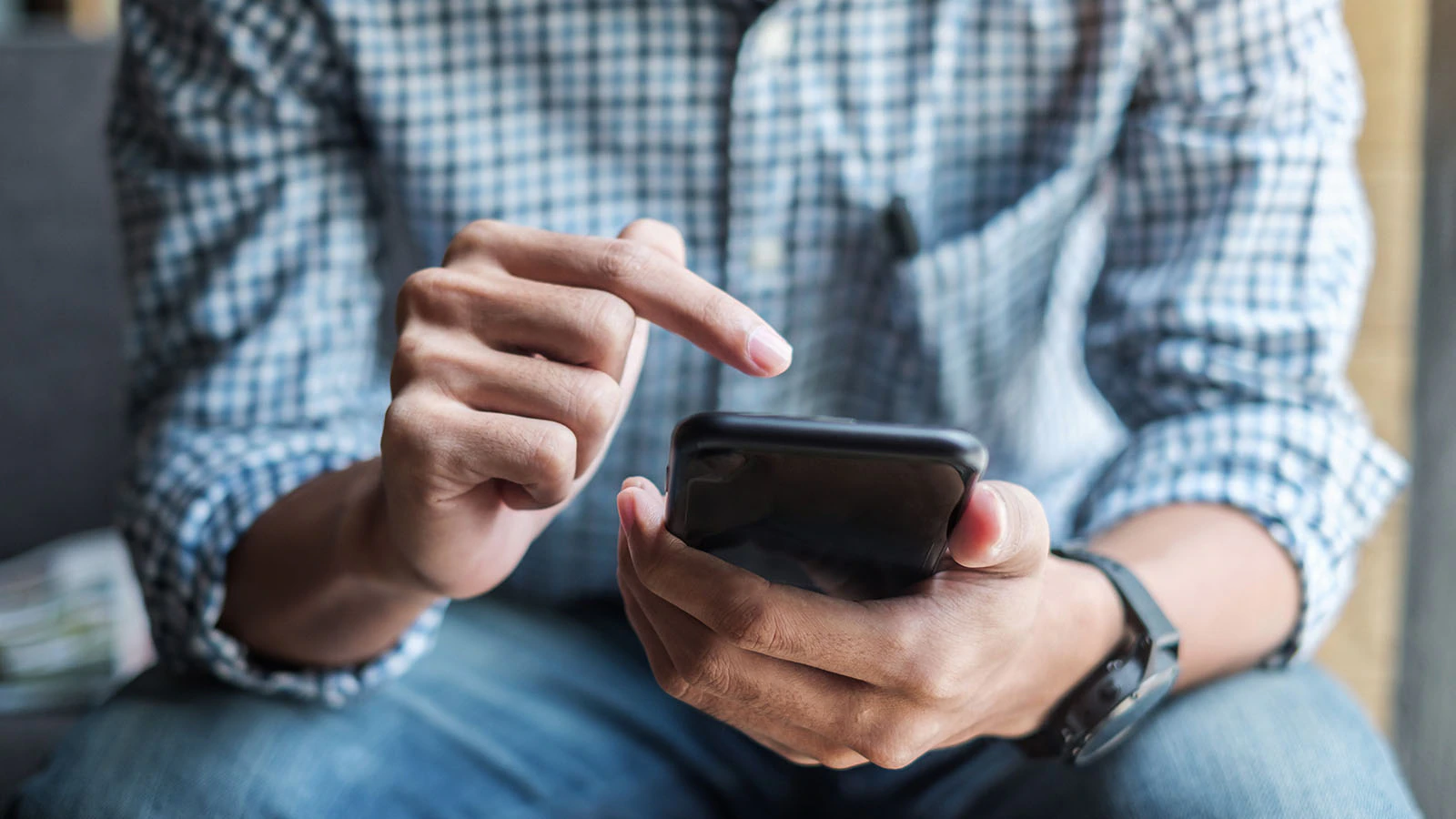 Close-up of a driver’s hands holding their smartphone away from view while scrolling on the screen.