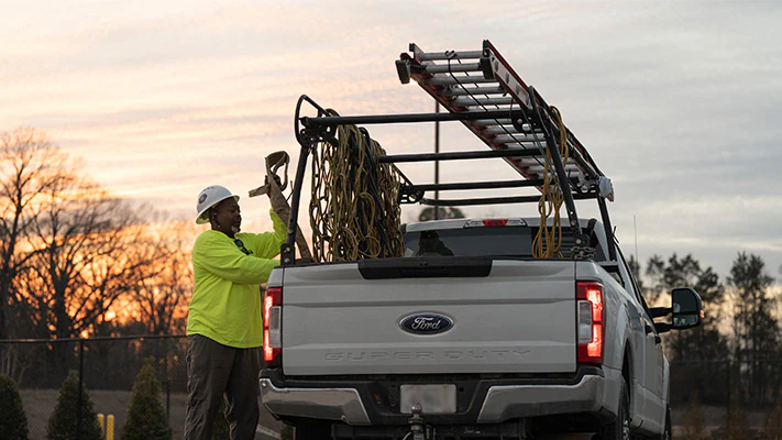 A Super Duty® truck owner gets equipment from the bed of their pickup.