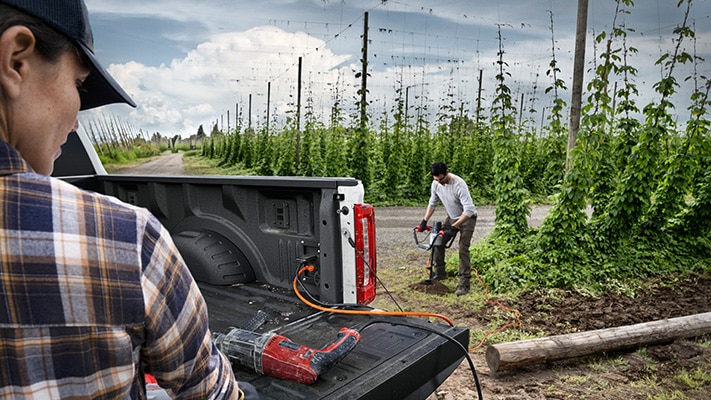 A Super Duty owner plugged into the Pro Power Onboard™ bed outlet goes to work with an electric auger.