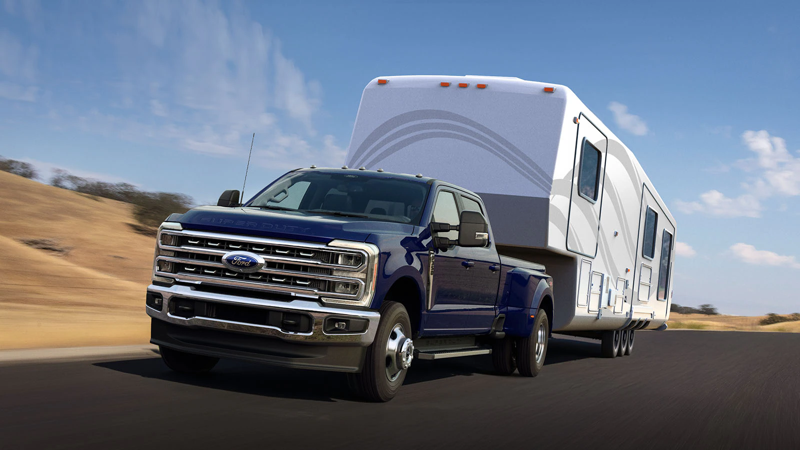 A Super Duty® truck tows a large camper along a country road.
